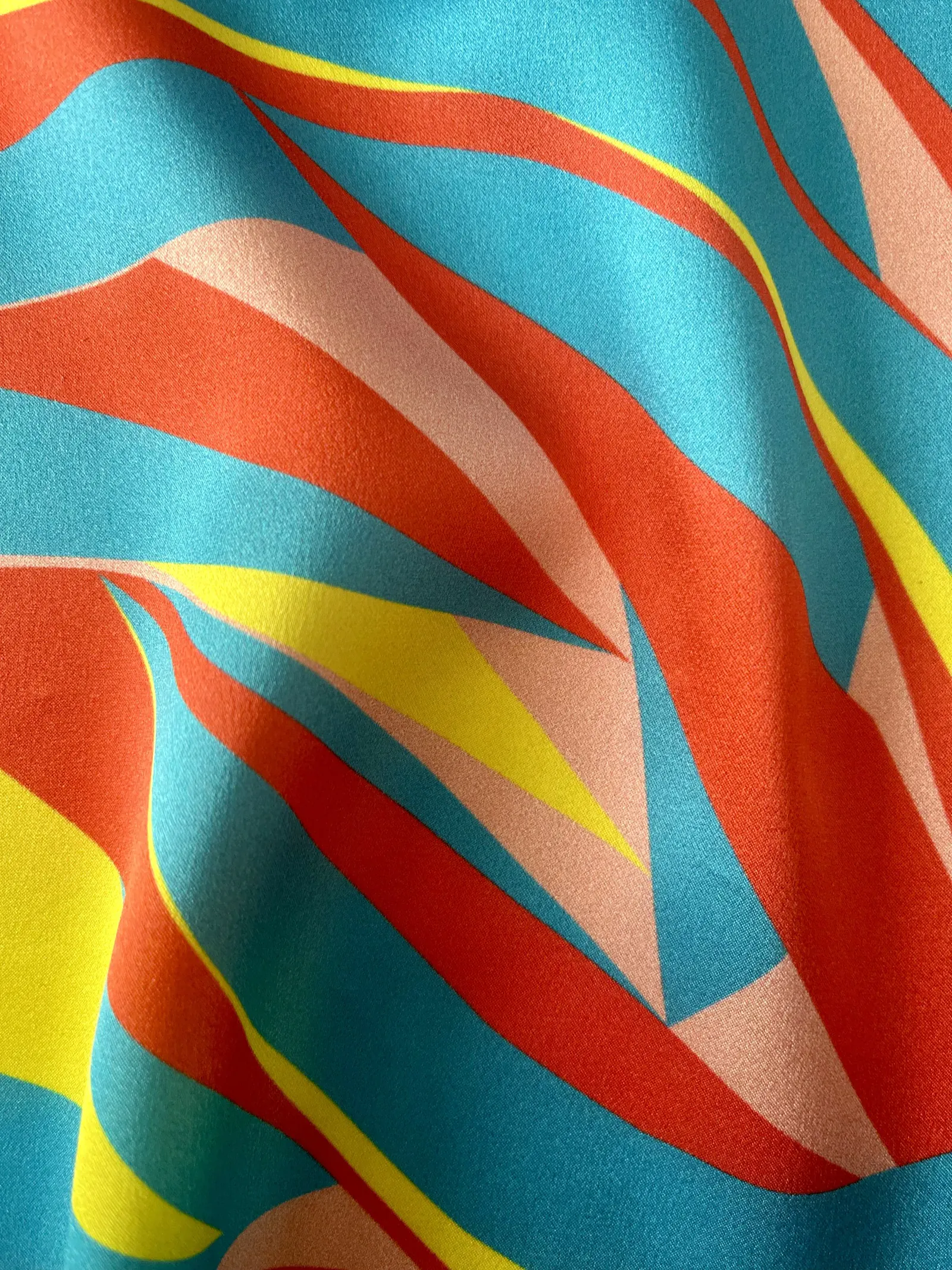 Bold bespoke textile design by Kika Pierides — sweeping curved bands in red, turquoise, yellow and pink, available as fabric by the metre
