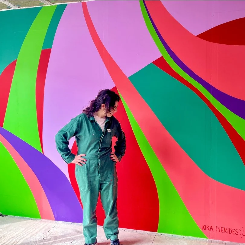 Kika standing in front of one of her large, colourful abstract paintings